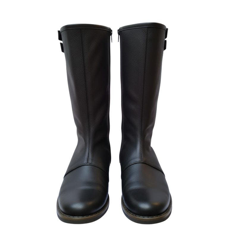 May include: A pair of black leather knee-high boots. The boots have a smooth texture, a zipper on the side, and a buckle detail near the top. The soles are a contrasting brown color.
