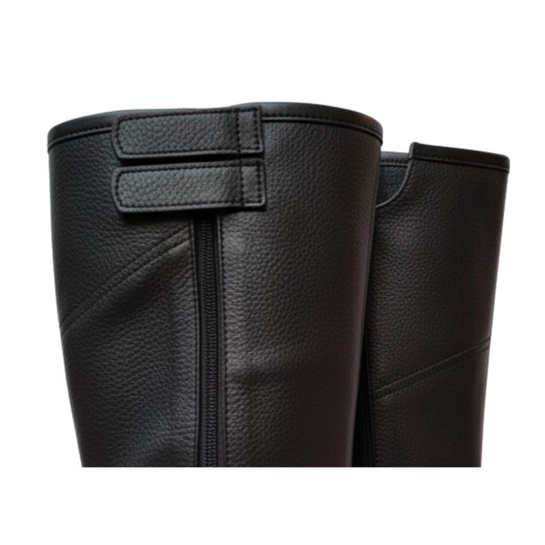 May include: Close-up of a pair of black leather riding boots. The boots have a textured surface, a zipper, and a buckle closure at the top. The boots are designed to be worn for equestrian activities or fashion.