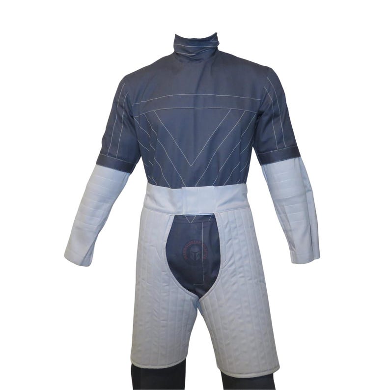 May include: A grey and white padded fencing suit. The upper body is grey with white stitching and a high collar. The lower portion is white, quilted, and covers the thighs. The suit has a white belt and long sleeves.
