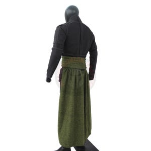 May include: A black outfit with a long green skirt and a wide green belt. The top is a black jacket with long sleeves. The outfit is displayed on a mannequin.