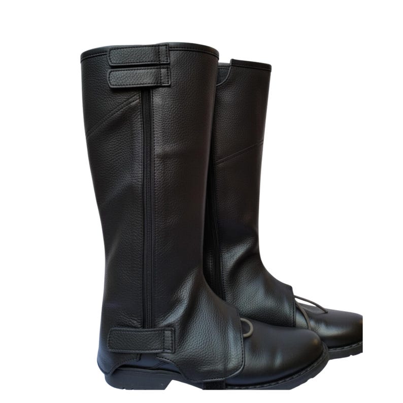 May include: A pair of black leather riding boots. The boots are knee-high with a textured finish and feature a zipper and adjustable straps. The boots have a classic design, suitable for equestrian activities.