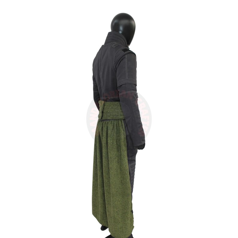 May include: A dark gray jacket with a high collar and a green skirt. The jacket has visible stitching and a buttoned closure. The skirt is a textured green fabric, creating a layered effect. The outfit is displayed on a mannequin.