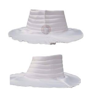 May include: Two white hats are shown. Each hat has a structured, cylindrical crown with horizontal, ribbed detailing. The wide brims have a scalloped edge. The hats appear to be made of a soft, flowing fabric. The hats are displayed against a white background.