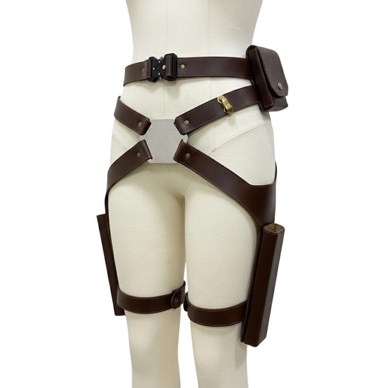May include: Brown leather utility belt with a black buckle, a small pouch, and two leg holsters. The belt features a silver metal plate and adjustable straps. The design is functional and stylish.
