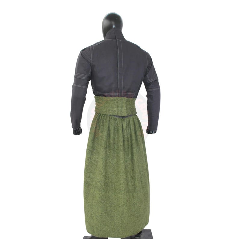 May include: A black jacket with long sleeves and a high collar, paired with a long, olive green skirt. The skirt has a high waist and a textured appearance. The outfit is displayed on a mannequin.