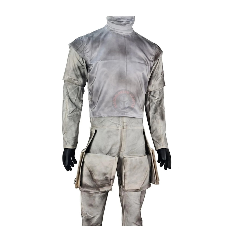 May include: A light gray costume with a high collar and long sleeves. The outfit includes a top and pants with large pockets. The costume has a weathered appearance, suggesting it is used. Black gloves are worn.