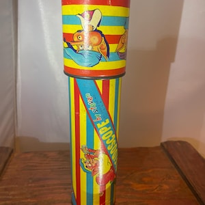 May include: A vintage kaleidoscope by Steven, featuring a colorful design with cartoon characters and vertical stripes in red, yellow, blue, and green. The text "KALEIDOSCOPE by Steven" is printed on the side.