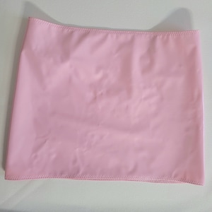 Puede incluir: Una falda corta de color rosa brillante hecha de un tejido sintético liso. La falda tiene un corte sencillo y recto y un dobladillo estrecho.