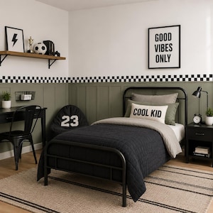 May include: A black metal bed frame with a dark gray quilted comforter, a light gray pillow, and a white rectangular accent pillow with the text "COOL KID" printed in black. The room features olive green wall paneling and a checkered border.