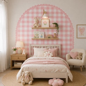 Puede incluir: Un dormitorio acogedor con una cama blanca, adornada con ropa de cama rosa y blanca, almohadas y un cojín en forma de flor. Un gran patrón de cuadros rosas decora la pared. Un conejito de peluche y una imagen enmarcada de una flor están en un estante. Una alfombra redonda completa la habitación.