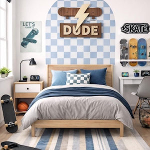 Könnte beinhalten: Ein Schlafzimmer mit Skateboard-Thema. Das Zimmer verfügt über einen Holzrahmen, blaue und graue Bettwäsche und einen gestreiften Teppich. Skateboards sind an der Wand und auf dem Boden ausgestellt, zusammen mit einem Schild mit der Aufschrift "DUDE". Ein Poster mit dem Text "LET'S HMMATT" ist ebenfalls zu sehen.