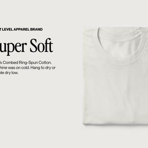 May include: A folded white t-shirt with a crew neck. The text "Super Soft" is displayed above the care instructions: "100% Combed Ring-Spun Cotton. Machine was on cold. Hang to dry or tumble dry low."
