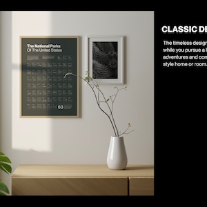May include: A framed poster with a black background and white text that reads "The National Parks Of The United States" and lists the names of all 63 national parks. The poster is hanging on a white wall next to a framed black and white photo. A vase with a single branch of twigs is on a wooden table in front of the poster.