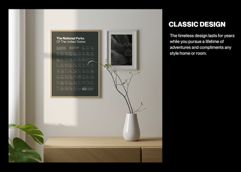 May include: A framed poster with a black background and white text that reads "The National Parks Of The United States" and lists the names of all 63 national parks. The poster is hanging on a white wall next to a framed black and white photo. A vase with a single branch of twigs is on a wooden table in front of the poster.