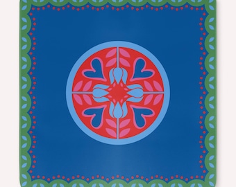 May include: Square blue coaster with a central circular design featuring pink and blue floral elements. The coaster has a green border with a dotted pattern and leaf-like shapes. The overall design is symmetrical and decorative.