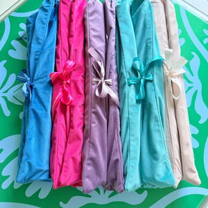 Puede incluir: Cinco bolsas de terciopelo plegadas en azul, rosa intenso, lavanda, turquesa y beige. Cada bolsa est&aacute; asegurada con una cinta de sat&eacute;n a juego atada en un lazo, con el texto The Merry Mahjong Co impreso en la superficie de la cinta.