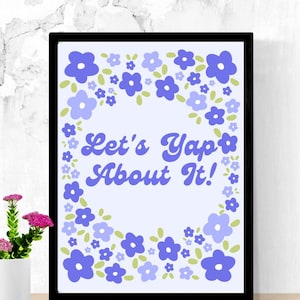 Puede incluir: Un estampado enmarcado con el texto "Let's Yap About It!" en una fuente retro, rodeado por un borde floral de flores azules y moradas con hojas verdes. El estampado está en un marco negro, y se ve un pequeño jarrón con flores rosas.