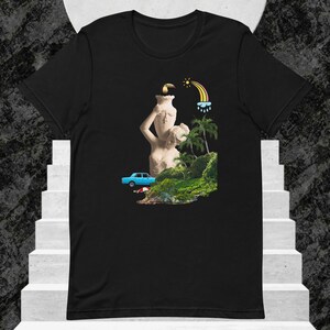 May include: Black t-shirt featuring a surreal collage. The design includes a classical statue, a blue car, palm trees, a rainbow, and a sun. The artwork has a vintage, artistic aesthetic.