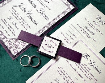 May include: A wedding invitation suite with a gothic theme. The invitation features the names Kimberly Leizure and Justin Cannon, with a skull and heart motif. Includes reply cards, details card, and a band with the text "Til Death Do Us Party". Two silver rings are also present.