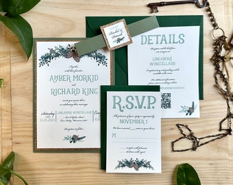 May include: A wedding invitation suite with a green and gold color scheme. The invitation features a floral design with pine cones and the text "Amber Morkid and Richard King". The RSVP card features a green and white floral design with the text "R.S.V.P. The pleasure of your reply is requested by November 1."