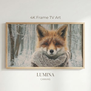 Puede incluir: Impresión en lienzo enmarcada que muestra un zorro con una bufanda en un bosque nevado. La obra de arte se titula "4K Frame TV Art" y "LUMINA CANVAS". El zorro tiene pelaje marrón rojizo y mira directamente al espectador.