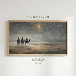 Puede incluir: Una impresión artística digital enmarcada que representa tres figuras silueteadas sobre camellos, viajando por un paisaje desértico bajo un cielo estrellado. Una estrella brillante brilla arriba. El marco es de madera clara. El texto "4K Frame TV Art" y "LUMINA CANVAS" son visibles.
