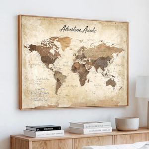 Puede incluir: Un mapa del mundo enmarcado con estética vintage, en tonos sepia y marrón. El texto Adventure Awaits aparece en la parte superior, y la esquina inferior izquierda incluye el texto The Adventures of Jim & Veronica con una cita debajo.