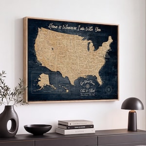Peut inclure: Une décoration murale rectangulaire présentant une carte des États-Unis de couleur beige sur un fond bleu foncé. Le texte Home is Wherever I Am With You est imprimé en haut, avec Our World Travels et les noms Tim & Beth en bas.