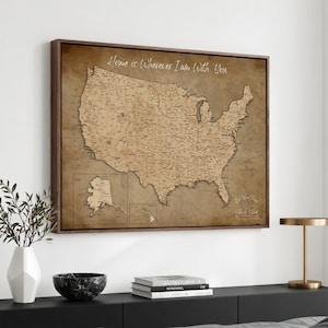 Op de afbeelding: Een rechthoekige wandkunstprint met een landkaart van de Verenigde Staten in vintage-stijl in bruin- en tinten. De kaart bevat Alaska en Hawaï in inzetkaders en toont bovenaan de tekst Home is Wherever I Am With You.
