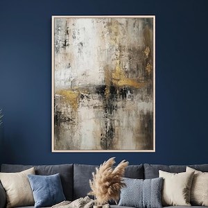 May include: Abstract art painting in a light wood frame. The artwork features a textured design with shades of white, gray, black, and gold. The painting has a vertical orientation and is displayed on a dark blue wall above a gray sofa.