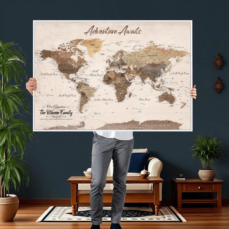 May include: A framed world map with a vintage aesthetic. The map features a sepia-toned background with brown and tan continents. The text "Adventure Awaits" is at the top, and "Our Adventures - The Blincoe Family" is at the bottom.