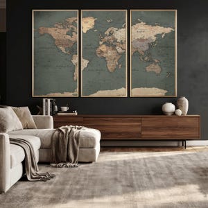 May include: Three framed world maps with a vintage aesthetic. The maps feature a muted color palette of brown and green, with gold frames. The maps are displayed above a wooden cabinet in a living room setting.