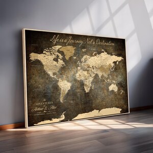 May include: A framed world map with a vintage aesthetic. The map features a dark brown background with gold-colored continents and country outlines. The text "Life is a Journey, Not a Destination" is at the top. The bottom text reads "The Adventures of Arthur & Alice."