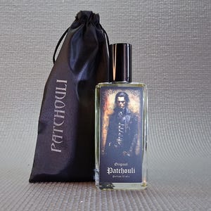 Puede incluir: Un frasco de perfume rectangular con tapa negra y etiqueta con retrato de hombre con ropa oscura. Junto a él, una bolsa negra con cordón y la palabra "PATCHOULI". El perfume está etiquetado como "Original Patchouli", 30 ml.