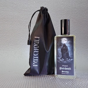 Puede incluir: Un frasco de perfume rectangular con tapón negro y una etiqueta con una ilustración oscura de una figura con túnica. Junto a él, una bolsa negra con cordón con la palabra "PATCHOULI" impresa. El frasco está etiquetado "Original Patchouli Strong", 30 ml.