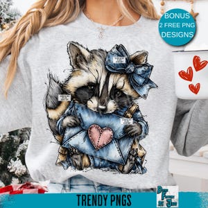 May include: A light gray sweatshirt featuring a raccoon illustration. The raccoon is holding a blue envelope with a pink heart. The raccoon has a blue bow and is wearing a blue outfit. The text "TRENDY PNGS" is at the bottom.