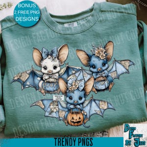 May include: A teal sweatshirt featuring three cartoon bats with large ears and blue wings. The bats are holding small baskets and a jack-o'-lantern. The text "TRENDY PNGS" and "DESIGN FACTORY BY JESS" are visible.