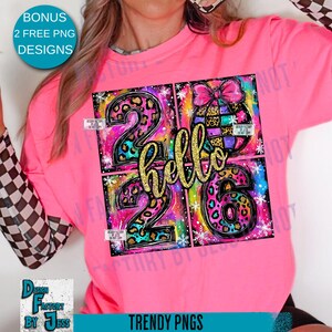 May include: A pink long-sleeved shirt with a colorful graphic design. The design features the numbers "26" and the word "hello" in gold glitter, with leopard print and rainbow accents. The shirt also has the text "TRENDY PNGS".