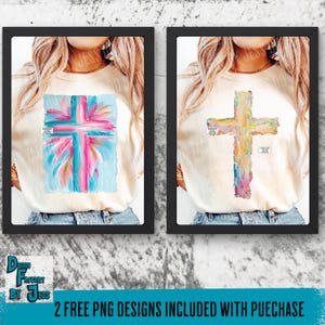 May include: Two framed art prints featuring colorful cross designs. One cross is painted in shades of pink, blue, and white, while the other is in yellow, orange, and purple. The text "DESIGN FACTORY BY JESS" is visible.