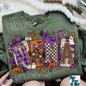 May include: An olive green crewneck sweatshirt featuring the word NANA in large block letters. The letters are decorated with purple plaid, orange pumpkin, black and white checkerboard, and leopard print patterns, surrounded by ghosts and bats.