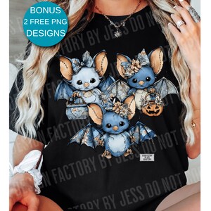 May include: Black t-shirt featuring a design of three blue bats with floral accents and patterned wings. Each bat holds a basket or a jack-o'-lantern. The shirt includes the text "BONUS 2 FREE PNG DESIGNS".