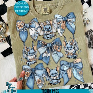 May include: Olive green Comfort Colors t-shirt featuring a design of blue bows and bat-like creatures holding jack-o'-lanterns. The design includes floral accents. Text on the shirt reads "BONUS 2 FREE PNG DESIGNS" and "TRENDY PNGS".