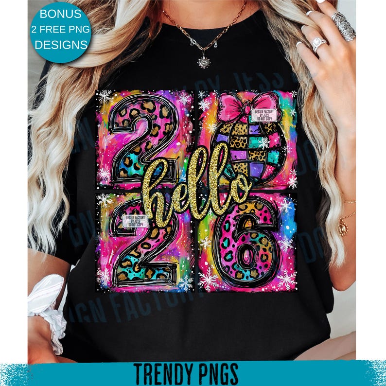 May include: Black t-shirt with a colorful graphic design. The design features the numbers "2026" in a leopard print pattern, the word "hello" in gold glitter, and a decorative globe with a pink bow. The shirt also has the text "TRENDY PNGS".