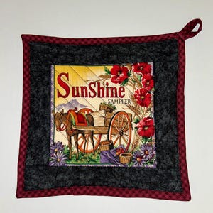 May include: Square quilted pot holder with a central image of a donkey pulling a cart with the text "Sunshine Sampler." The image is surrounded by red flowers, purple flowers, and a black and burgundy checkered border.
