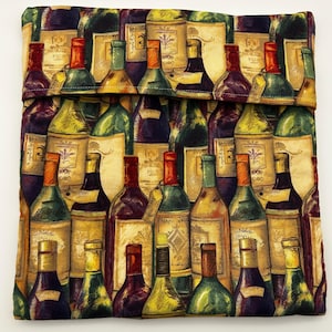 May include: A fabric wine bottle sleeve featuring a repeating pattern of wine bottles in various colors. The bottles have labels and are in shades of green, red, yellow, and purple. The sleeve is folded over at the top.