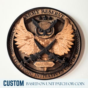 May include: A wooden Army Reserve plaque featuring an owl with crossed swords, wings spread, and the text "Strategic Initiatives Group." The plaque includes the text "Lt. Colonel Patrick R. Casserleigh July 2024-July 2025." The bottom reads "Custom Based on Unit Patch or Coin."