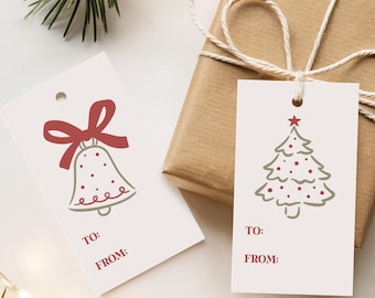 Puede incluir: Un regalo envuelto con una etiqueta blanca con un diseño de árbol de Navidad y una estrella roja. Otra etiqueta muestra una campana con un lazo rojo. Ambas etiquetas tienen impreso "TO:" y "FROM:". El regalo está atado con hilo.