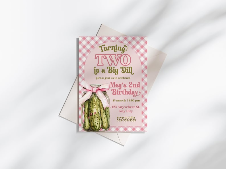 May include: A pink and white gingham-patterned birthday invitation with the text "Turning TWO is a Big Dill." The invitation features a watercolor illustration of a jar of pickles tied with a pink bow. The invitation is for Meg's 2nd birthday.