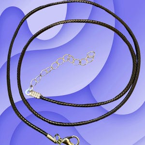 Puede incluir: Un cord&oacute;n de collar marr&oacute;n oscuro con un cierre y extensor de cadena dorados. El cord&oacute;n est&aacute; en bucle y descansa sobre un fondo azul y blanco. El cord&oacute;n del collar es un componente de joyer&iacute;a.