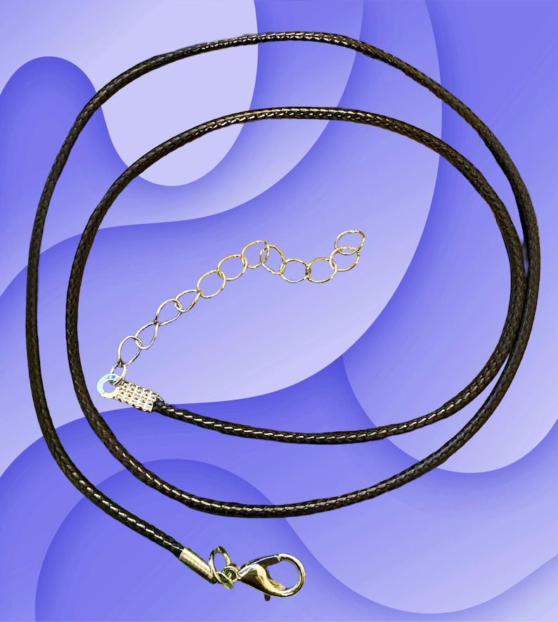 Puede incluir: Un cord&oacute;n de collar marr&oacute;n oscuro con un cierre y extensor de cadena dorados. El cord&oacute;n est&aacute; en bucle y descansa sobre un fondo azul y blanco. El cord&oacute;n del collar es un componente de joyer&iacute;a.